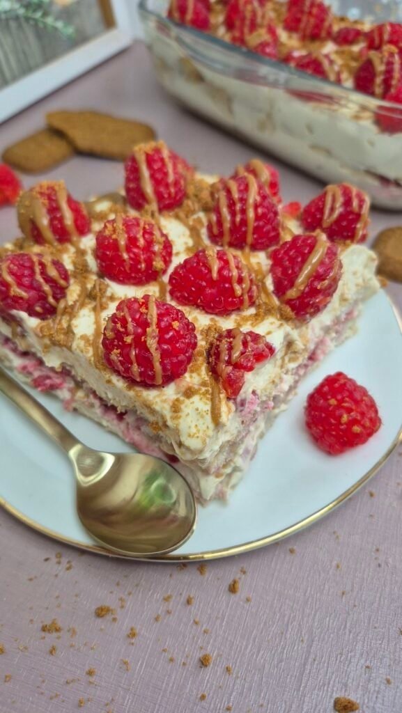 Slice of Lotus Biscoff raspberry tiramisu with fresh raspberries and crushed Lotus biscuits.
