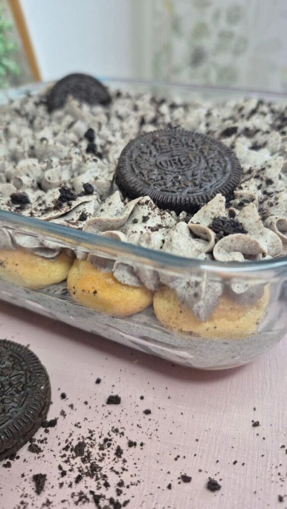 Oreo tiramisu in a glass dish topped with crushed Oreo cookies and a whole Oreo cookie