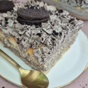 Slice of Oreo tiramisu topped with crushed Oreo cookies on a plate