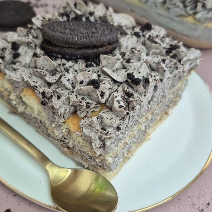 Slice of Oreo tiramisu topped with crushed Oreo cookies on a plate