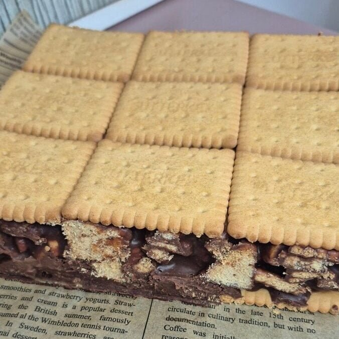 3-ingredient mozaic cake in a tray, topped with a neat layer of Petit Beurre biscuits and chocolate ganache filling underneath.