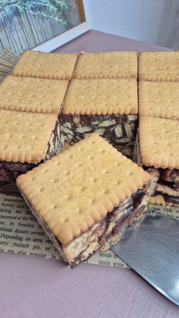 Square of 3-ingredient mozaic cake being lifted from the tray, showing the chocolate ganache and Petit Beurre biscuit mosaic layers.