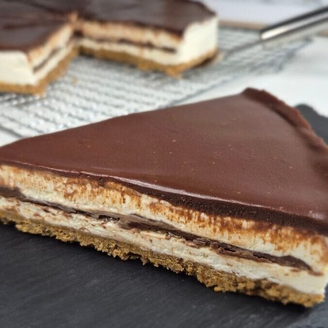 Slice of no-bake Nutella cake with biscuit base, mascarpone cream layers, and chocolate topping