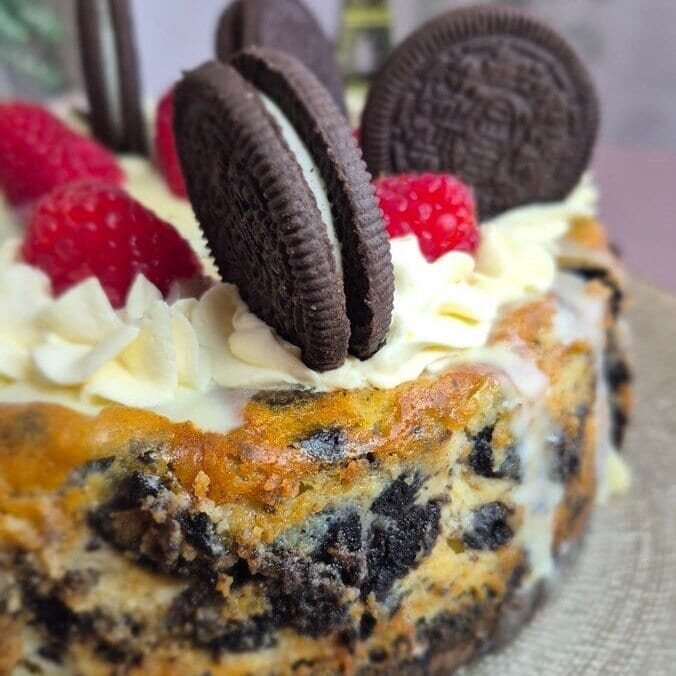 Oreo cheesecake topped with raspberries and Oreo cookies.