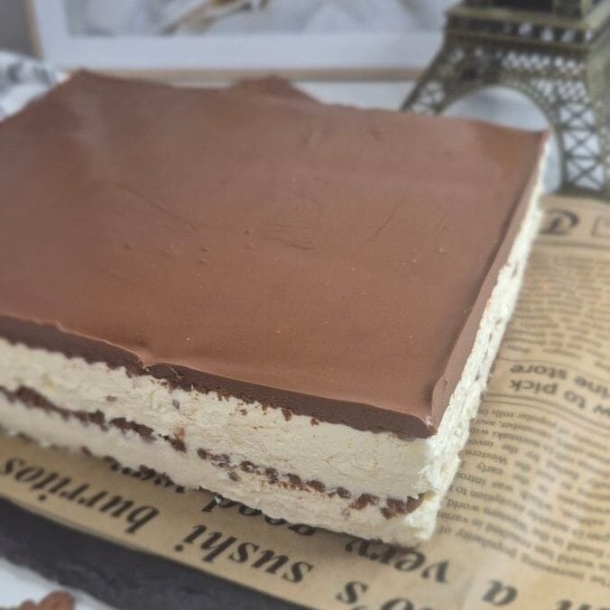Whole coffee biscuit cake with mascarpone cream and cocoa topping before slicing