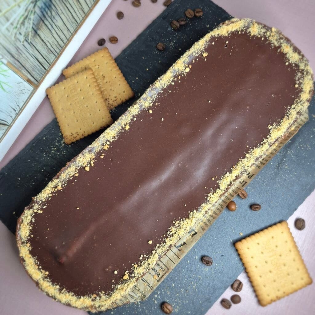 Whole no-bake chocolate biscuit cake with glossy chocolate topping on a serving tray