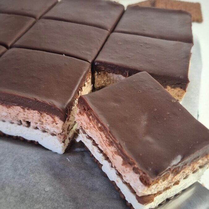 No-bake chocolate biscuit cake cut into squares, with mascarpone filling and chocolate ganache on top