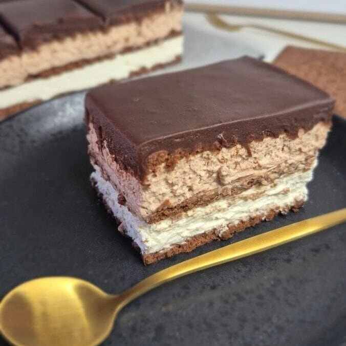Layered no-bake chocolate biscuit cake slice on a black plate