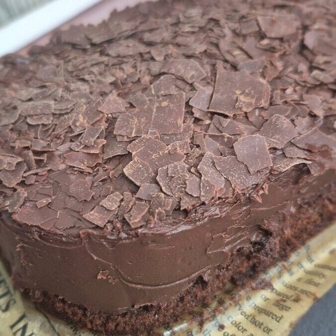 Moist chocolate cake with smooth chocolate topping and chocolate flakes on top