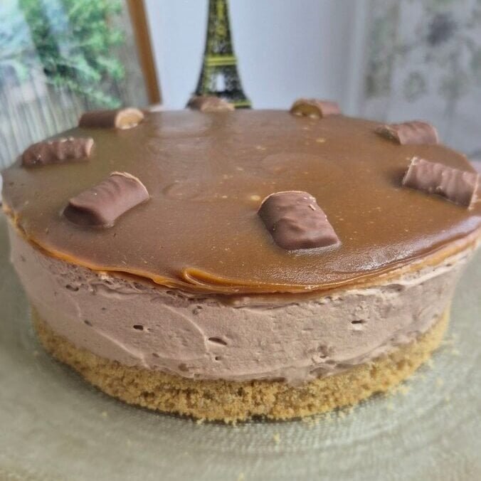 Whole Twix caramel cheesecake with a biscuit crust, creamy mascarpone filling, and glossy caramel topping