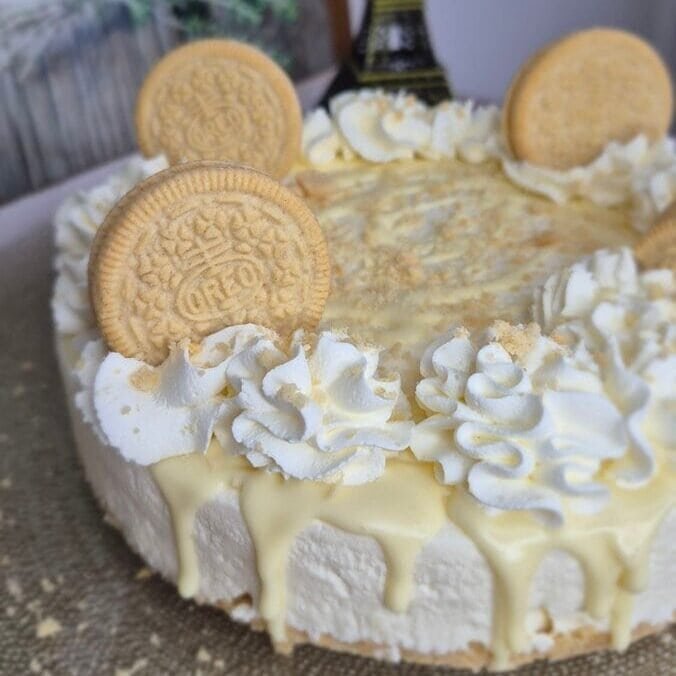 Whole Golden Oreo cheesecake with cream topping, cookie crumbs, and Golden Oreo cookies on top