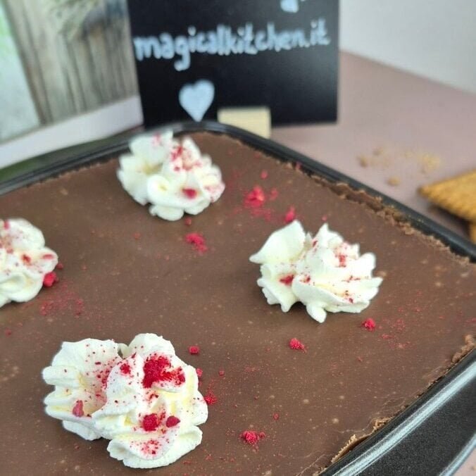 Whole biscuit cake topped with chocolate ganache and whipped cream rosettes with raspberries