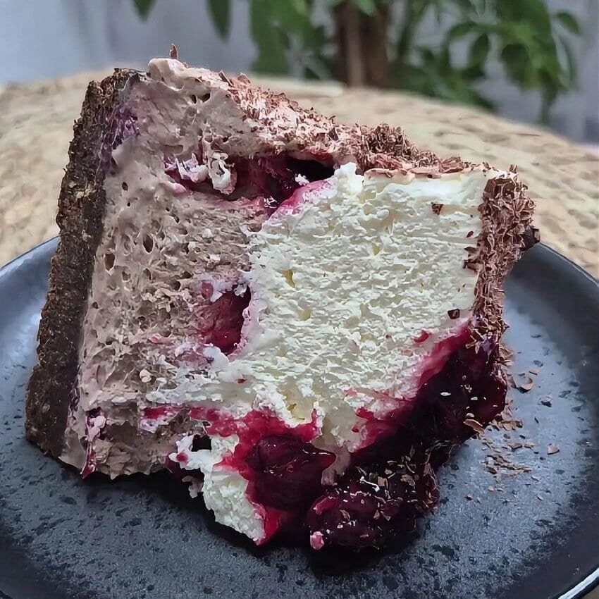 Slice of no-bake Black Forest cake with mascarpone filling, cherry layer, and chocolate crumb coating on a plate