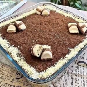 Kinder Bueno tiramisu in a glass dish topped with cocoa powder and pieces of Kinder Bueno