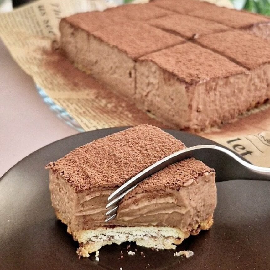 Slice of Nutella tiramisu squares on a plate with a fork, cocoa-dusted top and creamy mascarpone layer
