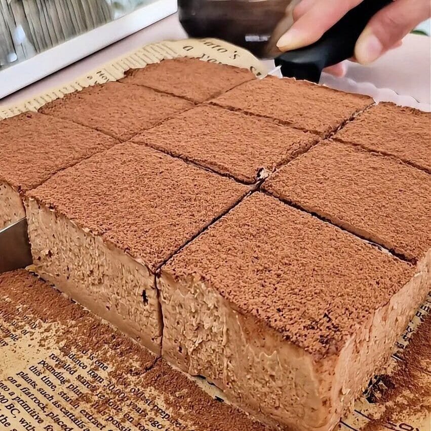 Cocoa-dusted Nutella tiramisu squares being sliced in the pan