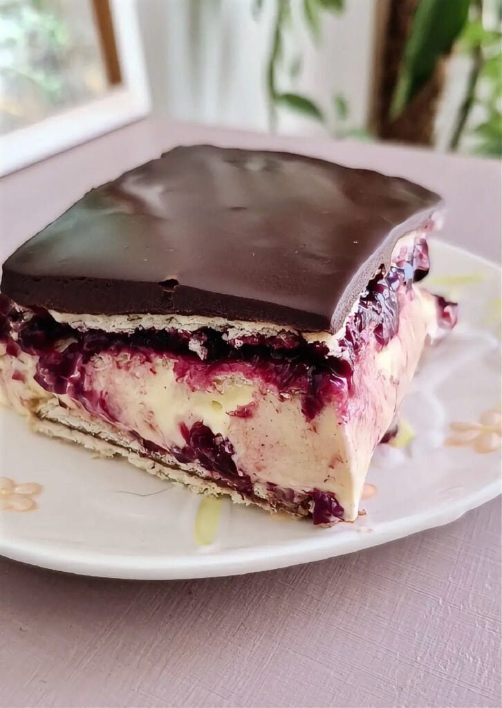 Slice of no-bake Nutella cake with vanilla mascarpone, berry layer, biscuit layer, and chocolate ganache