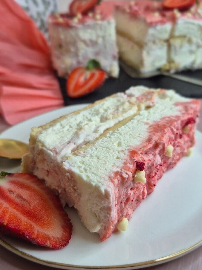 Side view of strawberry tiramisu cake slice with mascarpone cream layers, ladyfingers, and strawberry topping