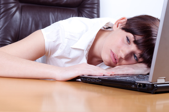 Tired young businesswoman falling asleep behind the desk