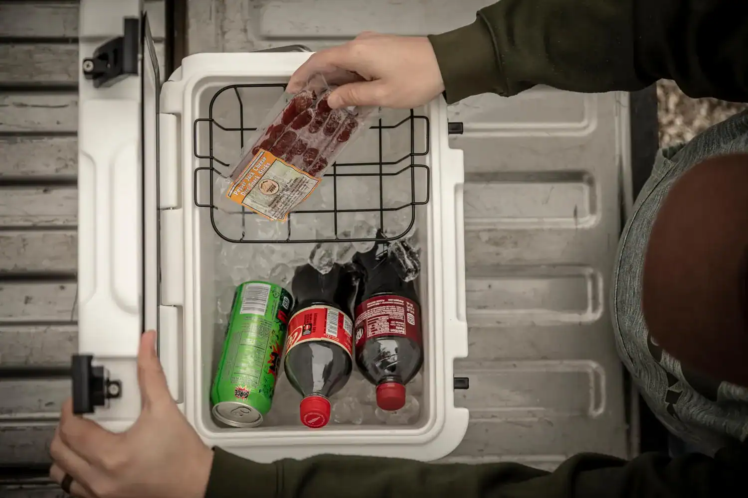 person putting drinks and food in cooler with basket
