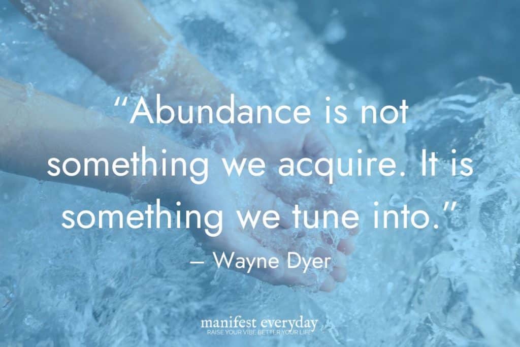hands splashing in clear blue water with quote text that reads “Abundance is not something we acquire. It is something we tune into.” – Wayne Dyer manifesteveryday.com