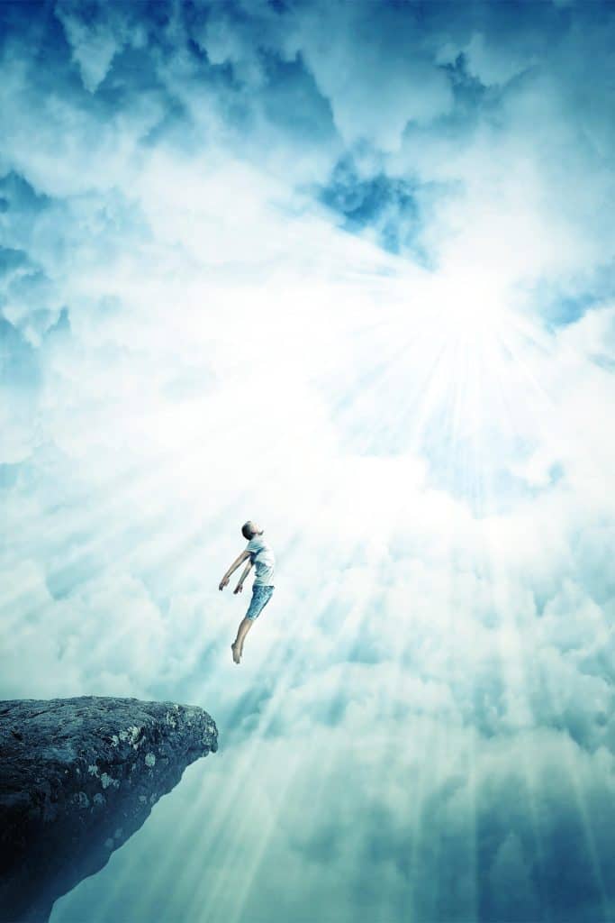 person flying off a cliff towards a bright white light in the sky signifying astral travel