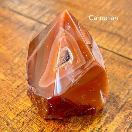 shiny, red colored carnelian point on wooden background