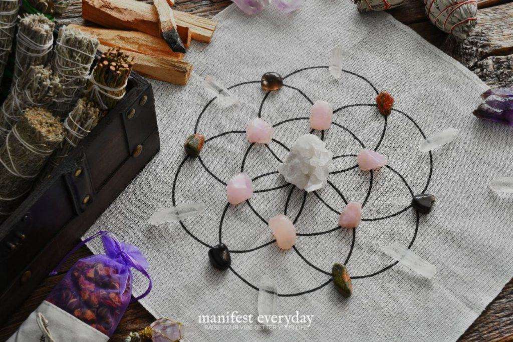 Example of a crystal grid with various types of healing crystals, palo santo, herbs, and sage smudge sticks