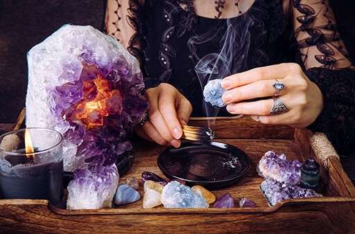 a woman cleanses her crystals with palo santo