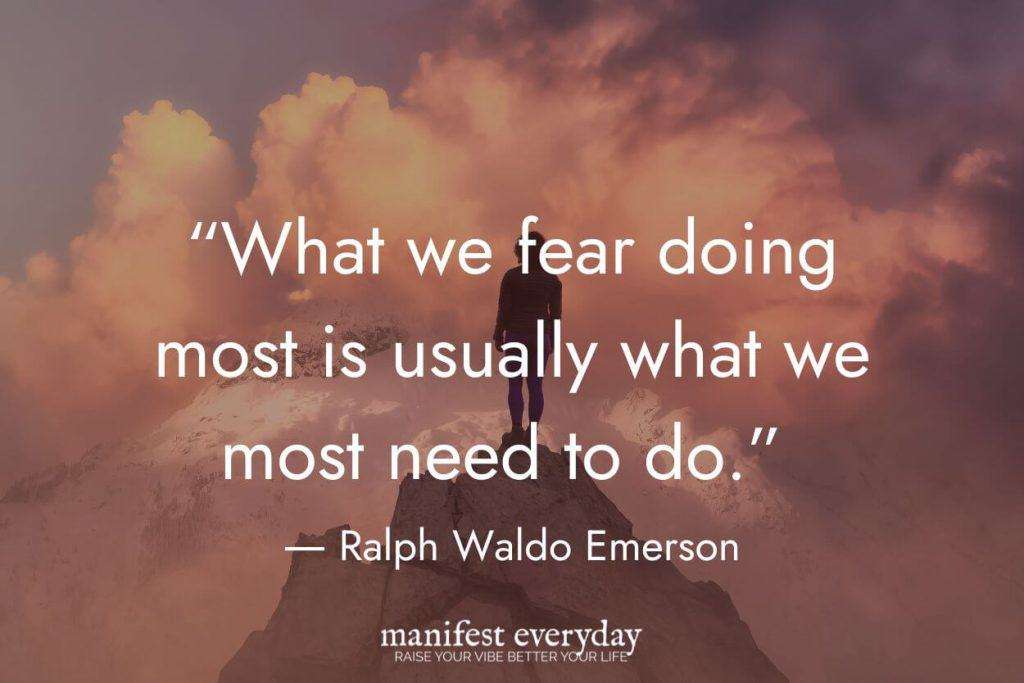 woman at the top of a mountain with pink cloudy sky with quote text that reads “What we fear doing most is usually what we most need to do.” - Ralph Waldo Emerson manifesteveryday.com