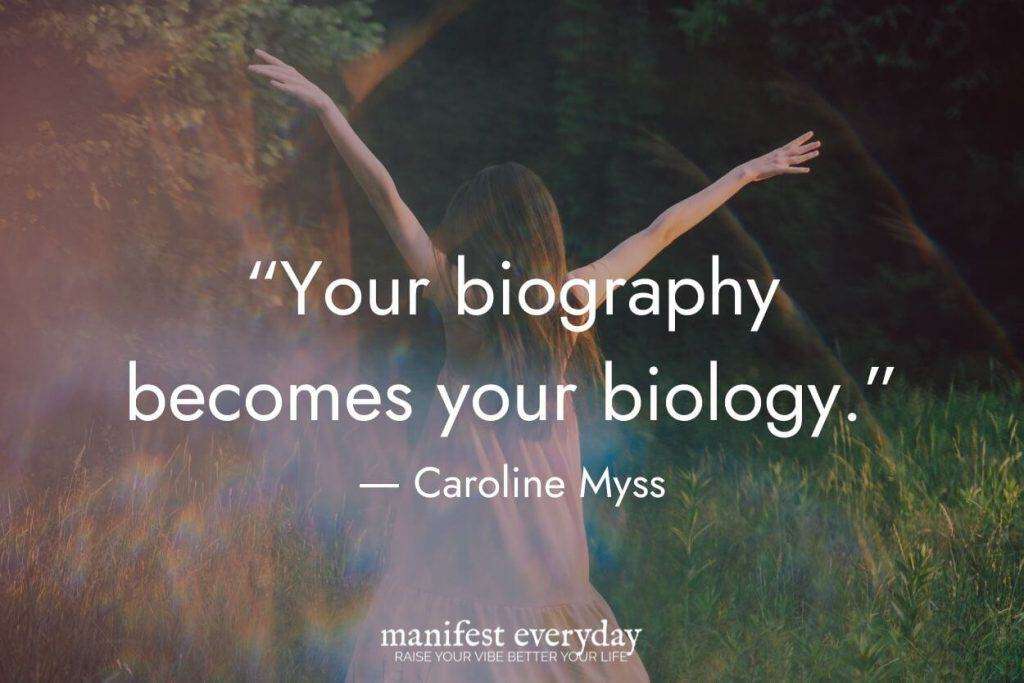 A motivational image featuring a silhouetted figure with arms raised against a natural background. The quote by Caroline Myss reads "Your biography becomes your biology." Also includes "manifesteveryday.com" branding.