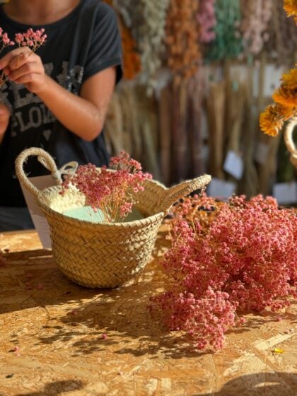 Ramos de flores rosas y amarillas en cesta de mimbre en floristería artesanal.