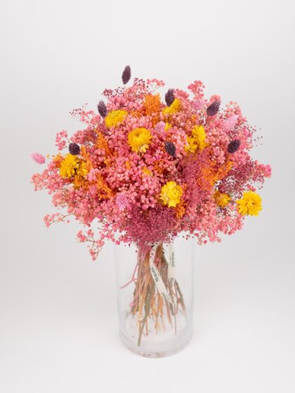 Ramo de flores en tonos rosa, amarillo y morado en jarrón de cristal.