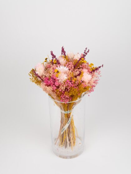 Ramo de flores secas en jarrón de cristal con tonos rosados y amarillos.