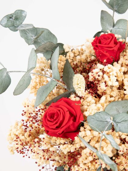 Rosas rojas, flores secas y eucalipto en arreglo floral elegante y natural.