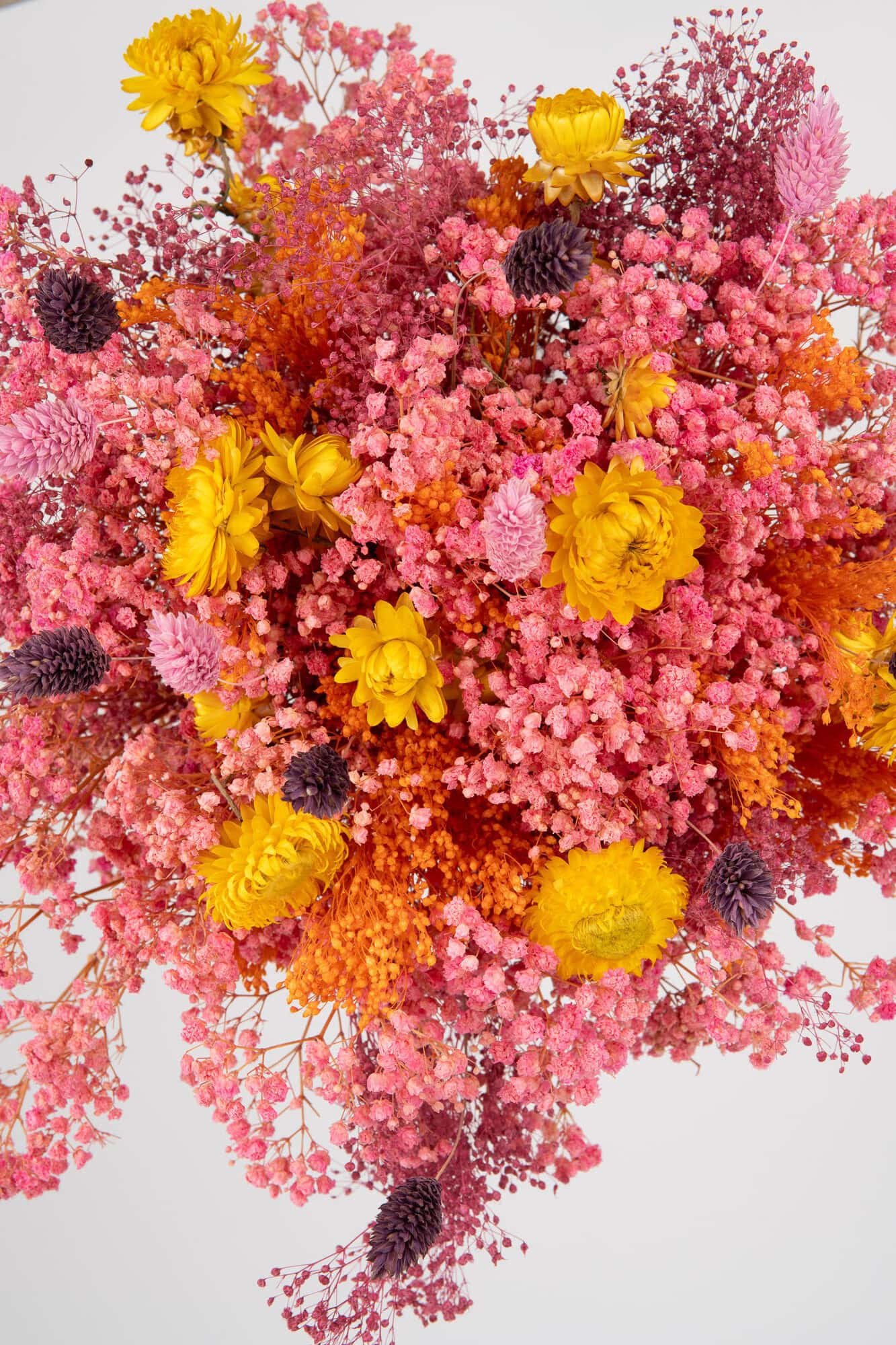 Ramo de flores vibrantes con rosas, craspedia y gypsophila en tonos rosados y amarillos.