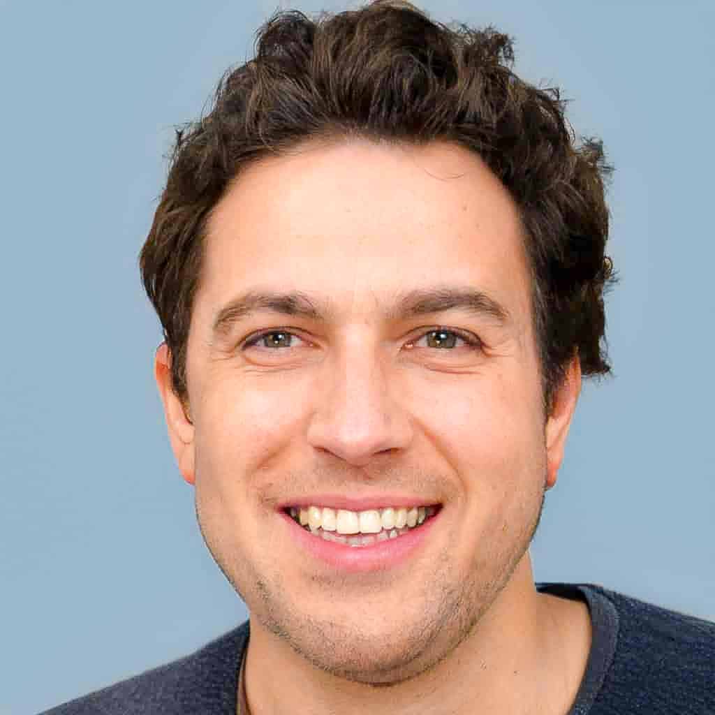 Ein Mann mit lockigem Haar lächelt in die Kamera.