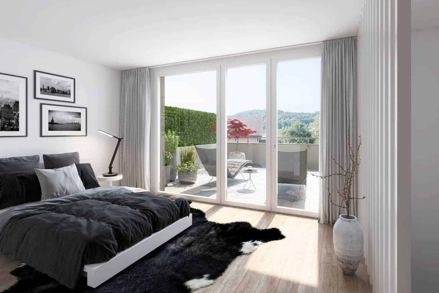 Modern bedroom with a large bed, glass sliding doors leading to a balcony overlooking a scenic view, and minimalistic decor.