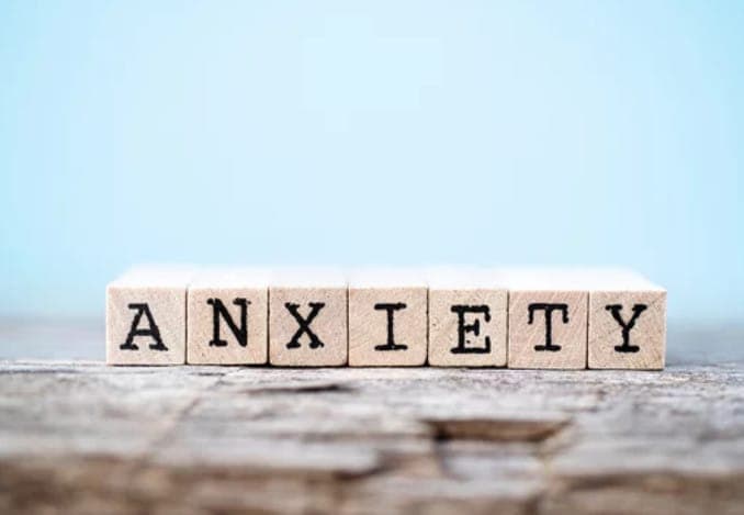 Wooden blocks spelling 'Anxiety' on textured surface.