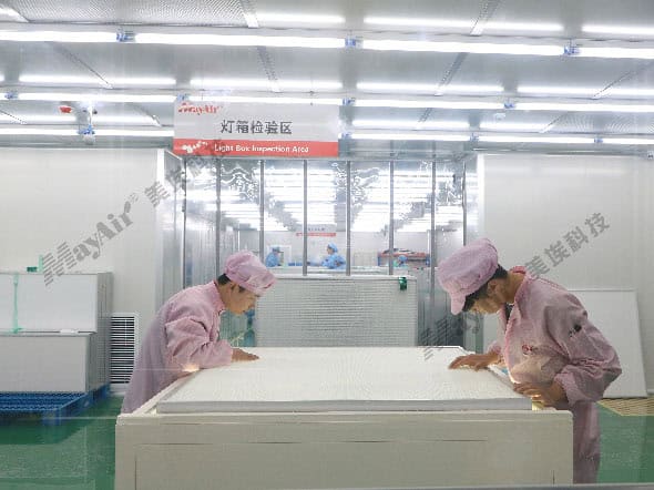 High-tech cleanroom manufacturing facility at MayAir Group with workers inspecting filtration products in a sterile environment.