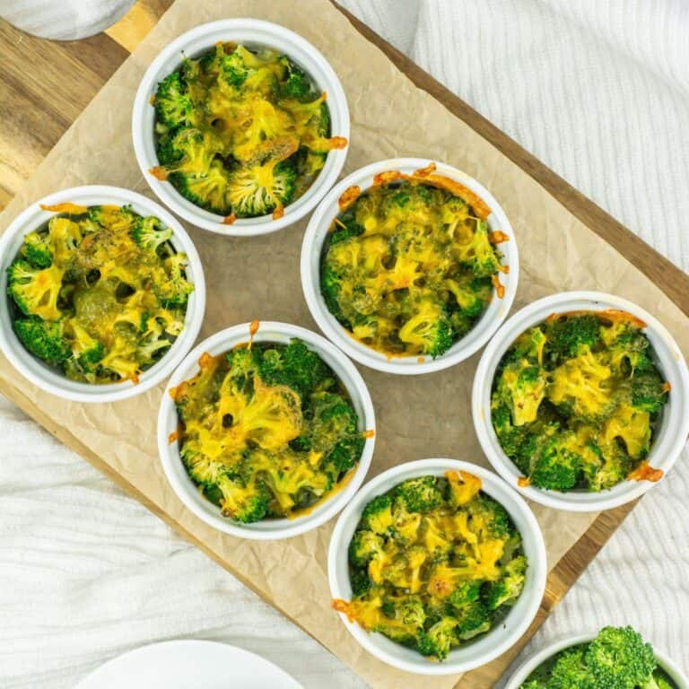Overhead shot of various 3 Ingredient Broccoli Cheese Casserole in white ramekins on a wooden board