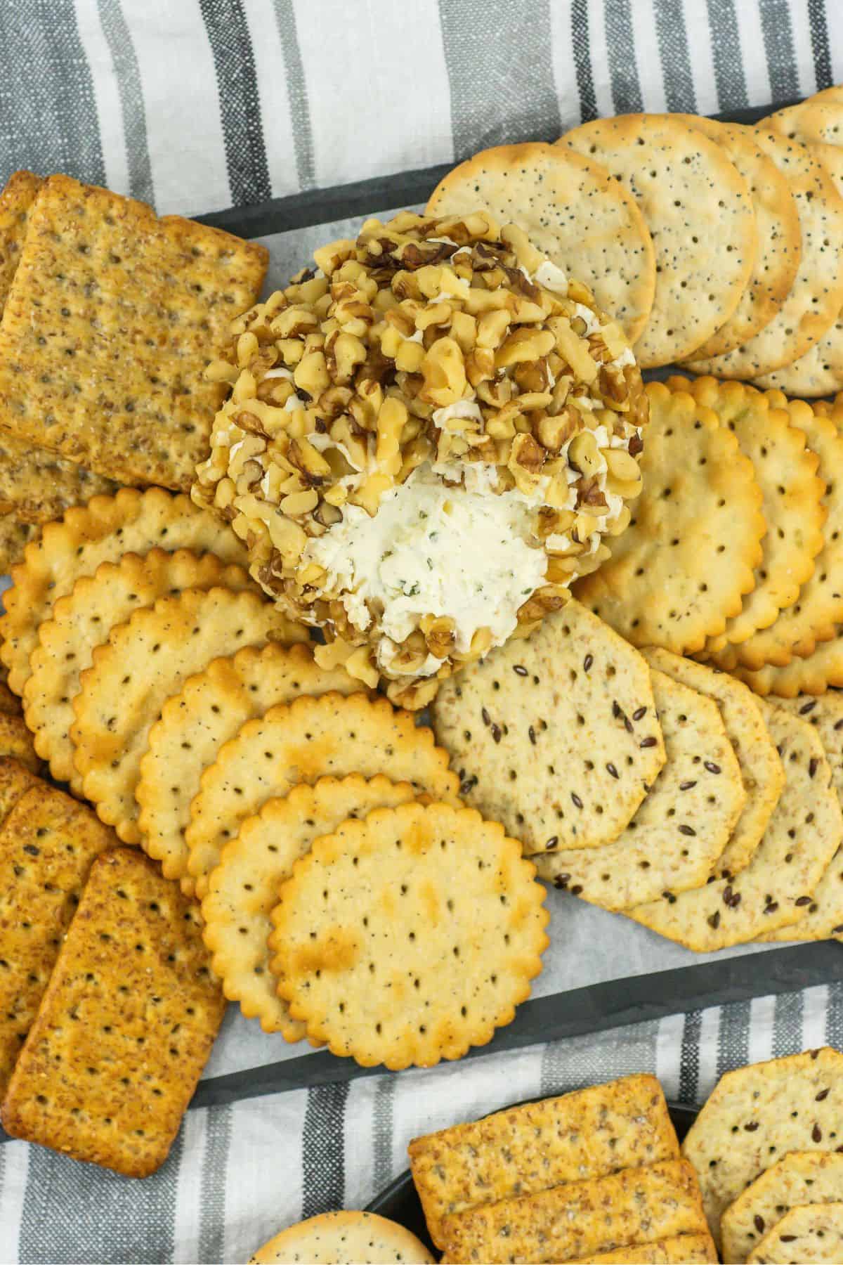 overhead shot of a cheese ball covered in walnuts with a portion scooped out surrounded by a variety of crackers