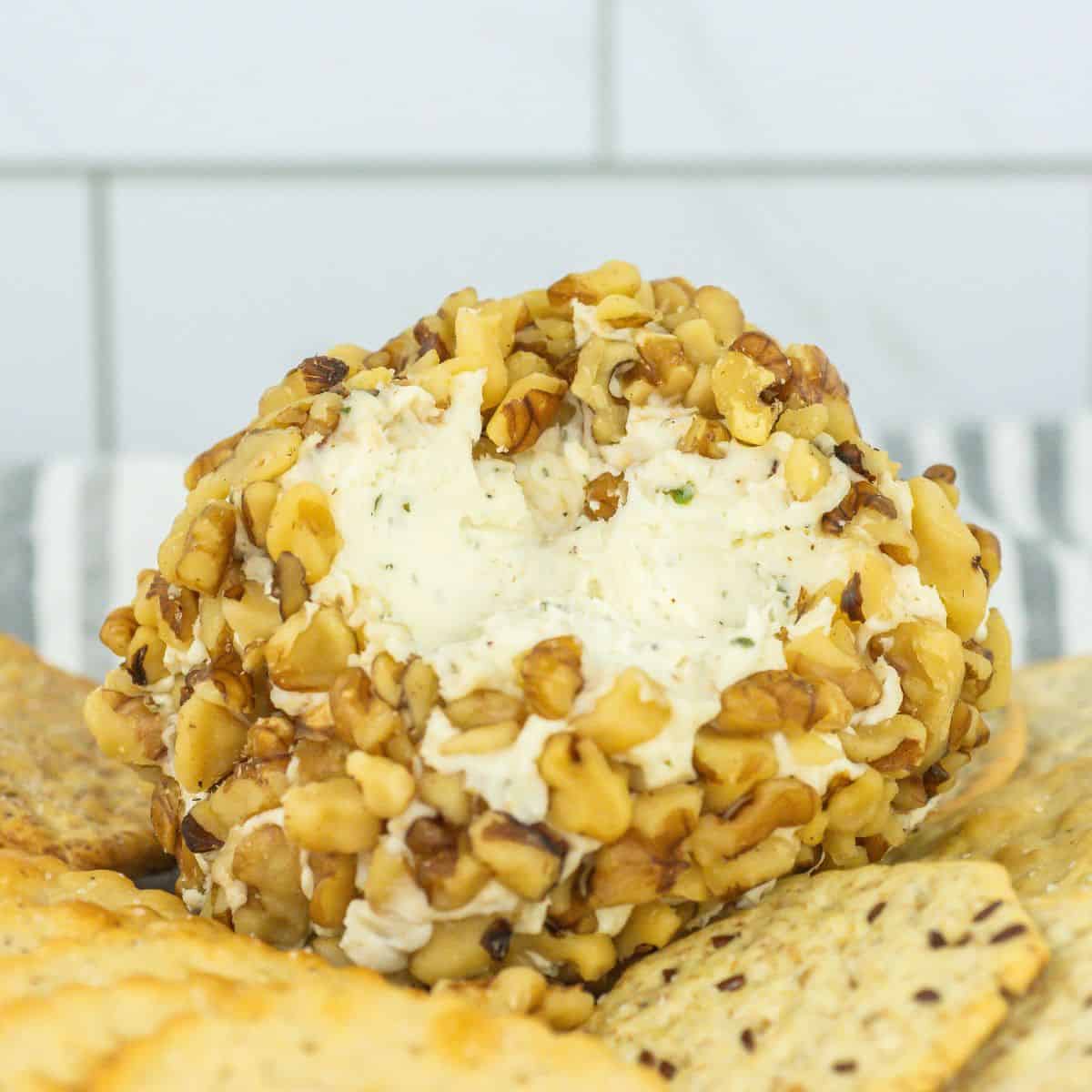 close-up of cheese ball covered in chopped walnuts with a portion scooped out