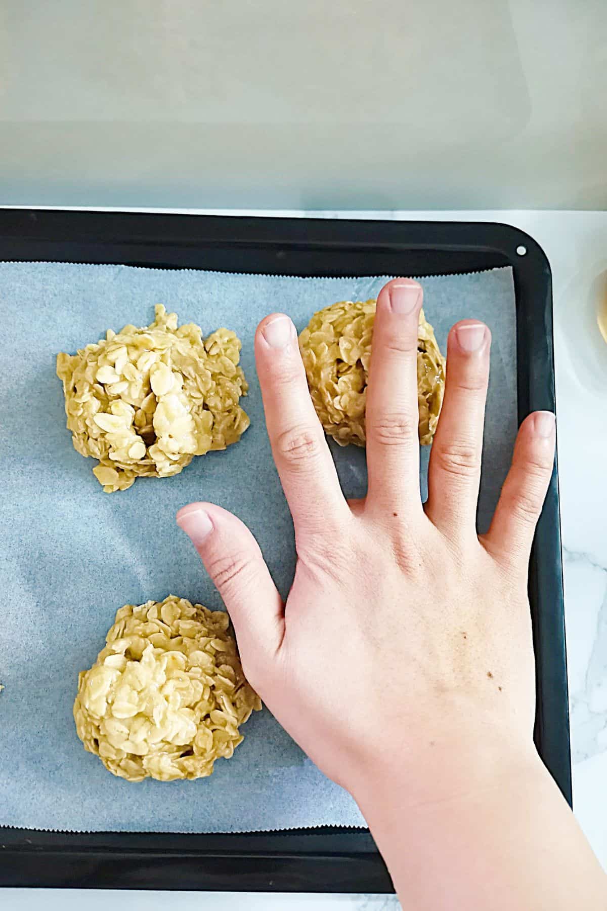 flattening cookies into round shapes with the palm of the hand