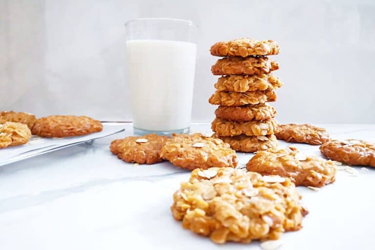 a few 3 ingredient oatmeal cookies stacked, with more cookies and a glass of milk on the side