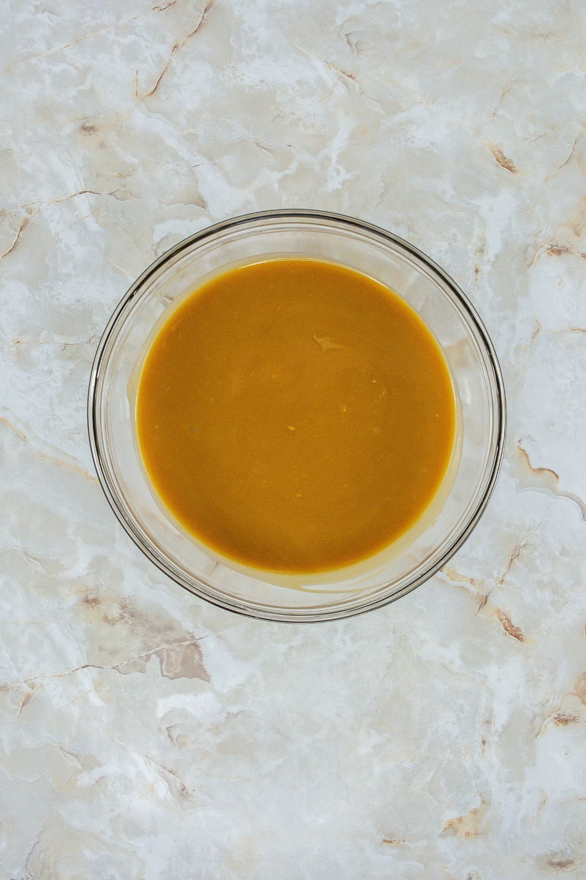 a mixture of creamy peanut butter and unsalted butter in a glass bowl