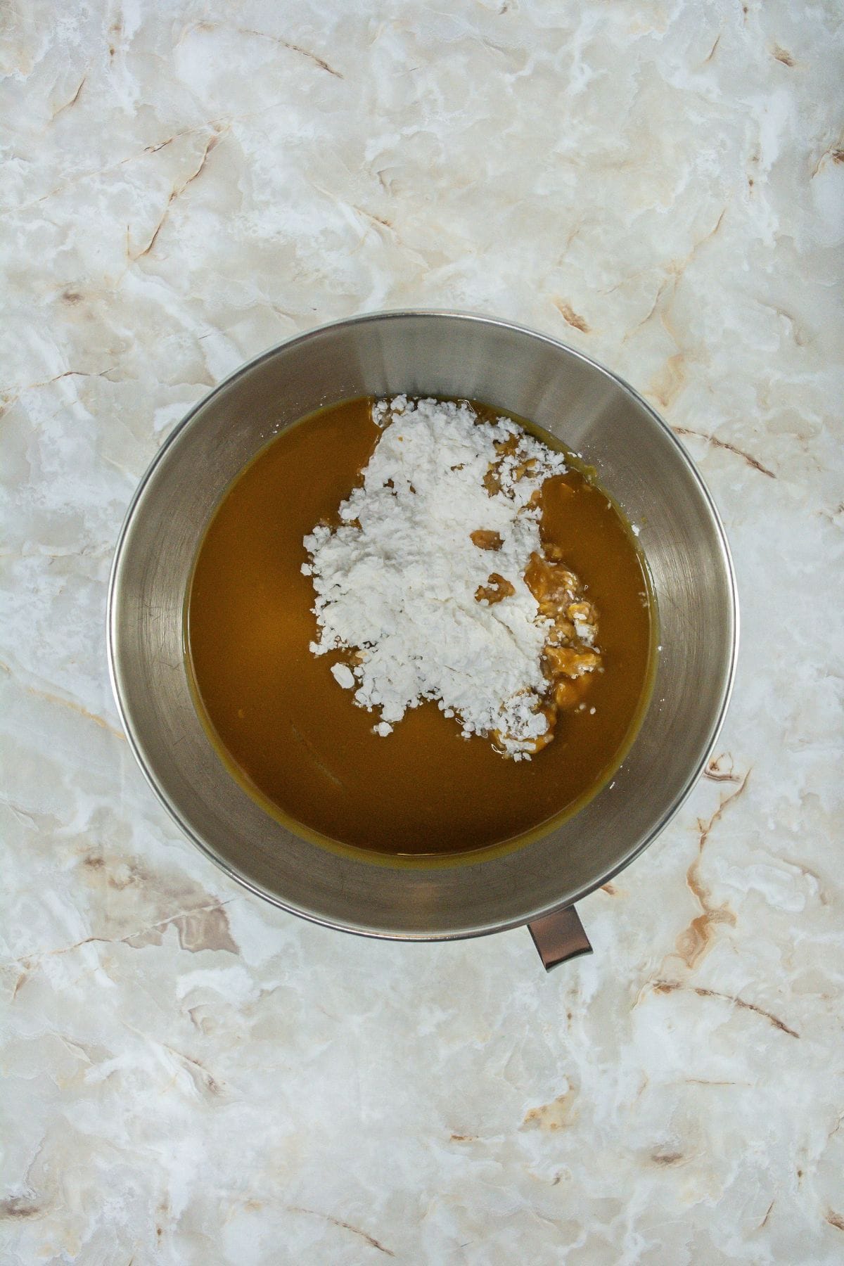 a mixture of creamy peanut butter and unsalted butter being mixed with a powdered sugar in a stand mixer bowl