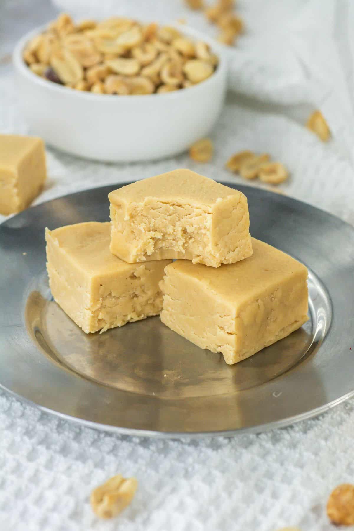 a plate of three peanut butter fudge squares with a bite on one piece