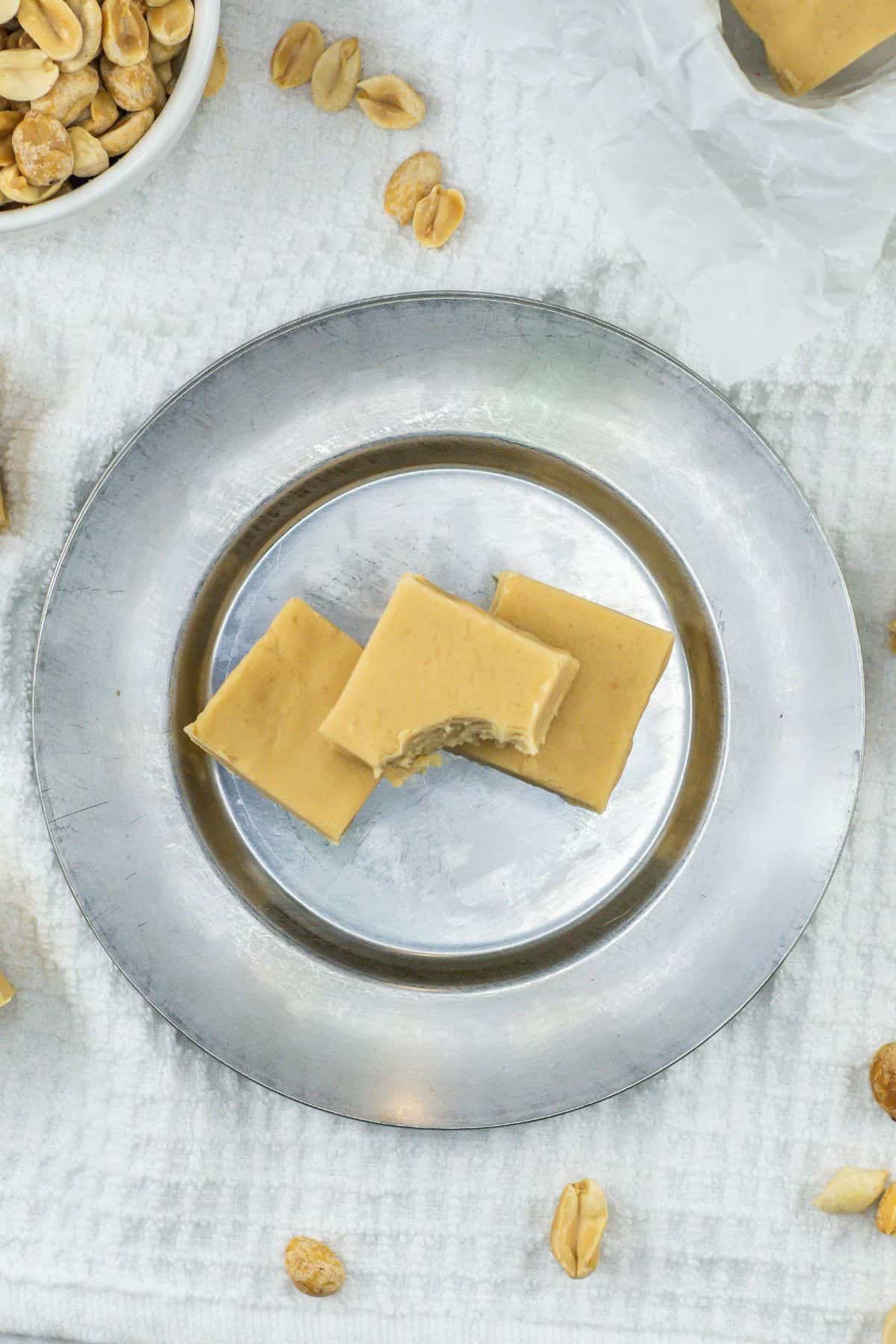 a plate of three peanut butter fudge squares with a bite on one piece