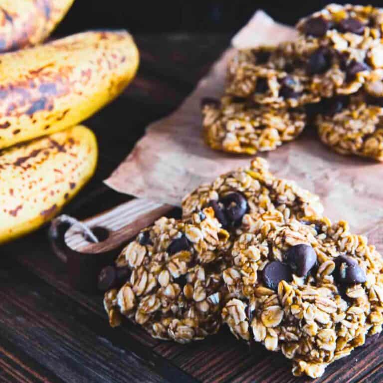 3 ingredient banana oatmeal cookies stacked on top of each other next to a bunch of bananas